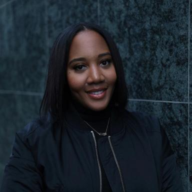 Woman with shoulder length black hair wearing black jacket smiles at camera